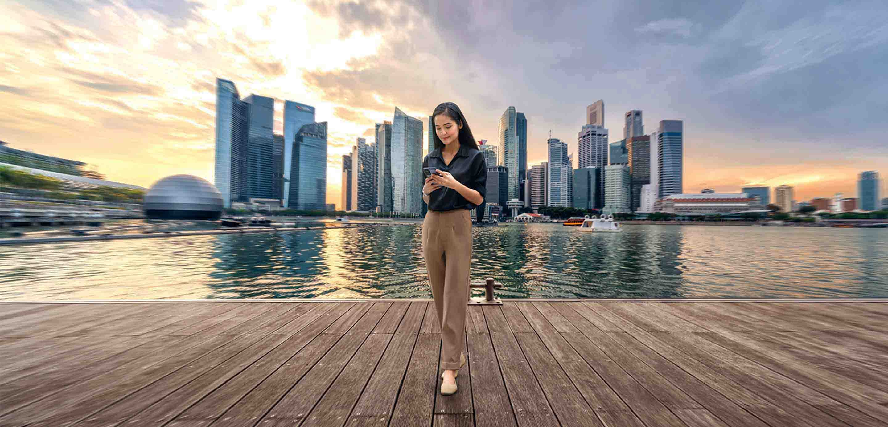 Woman standing at harbour front in Singapore using mobile phone